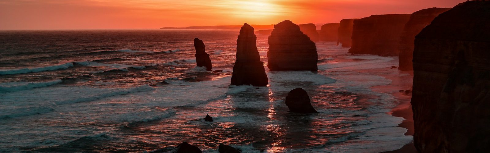 silhouette of stone on seashore during golden hour