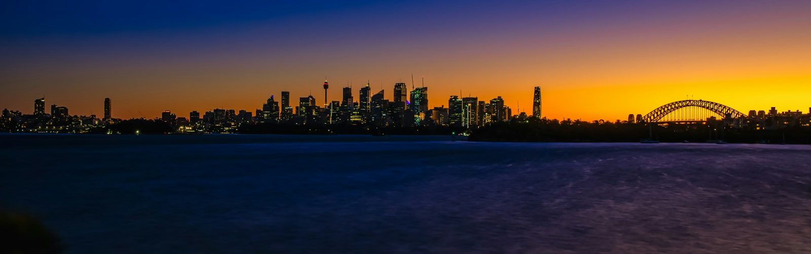 a view of a city at sunset with a bridge in the foreground