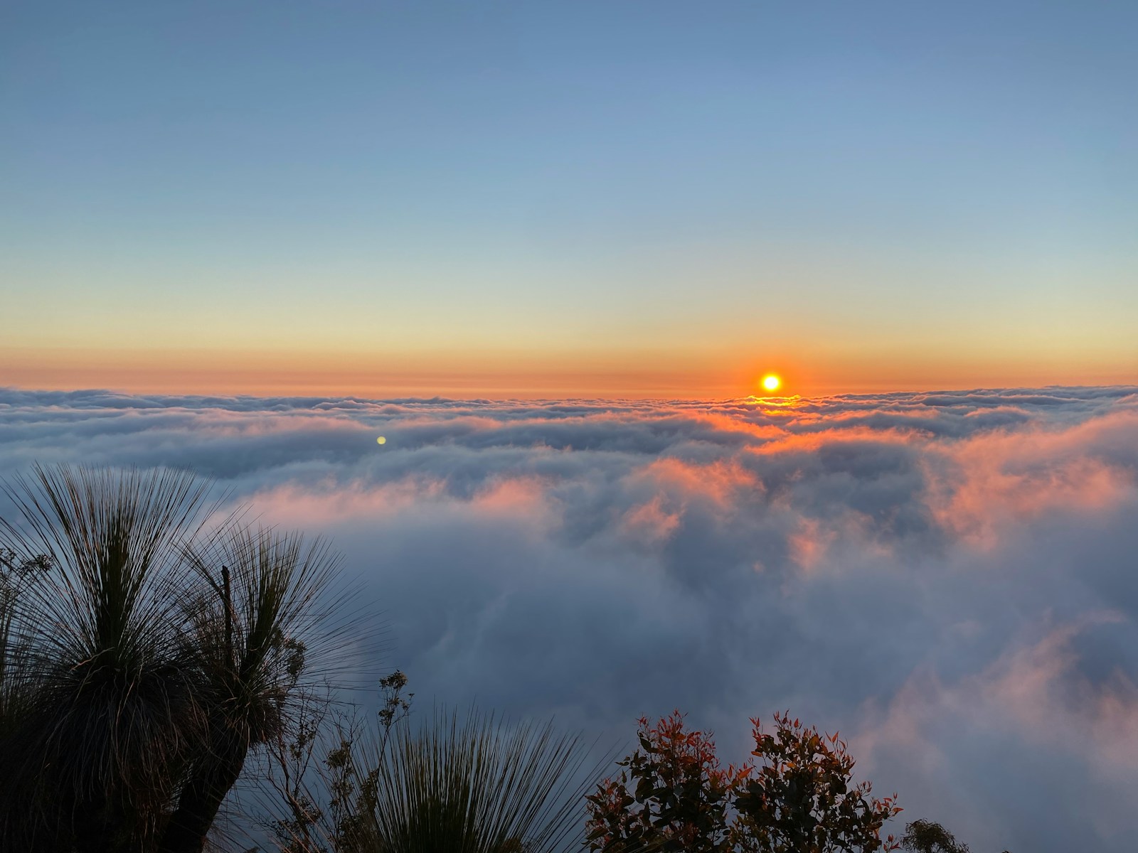 Photo by Tim the sun is setting over the clouds in the sky